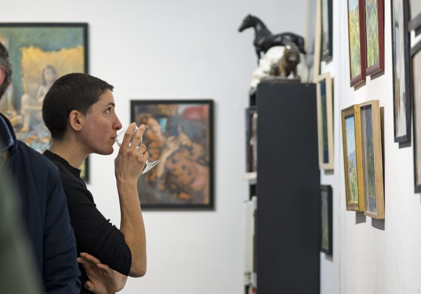 Jeune femme qui boit un verre de vin pendant un vernissage dans une galerie d'art